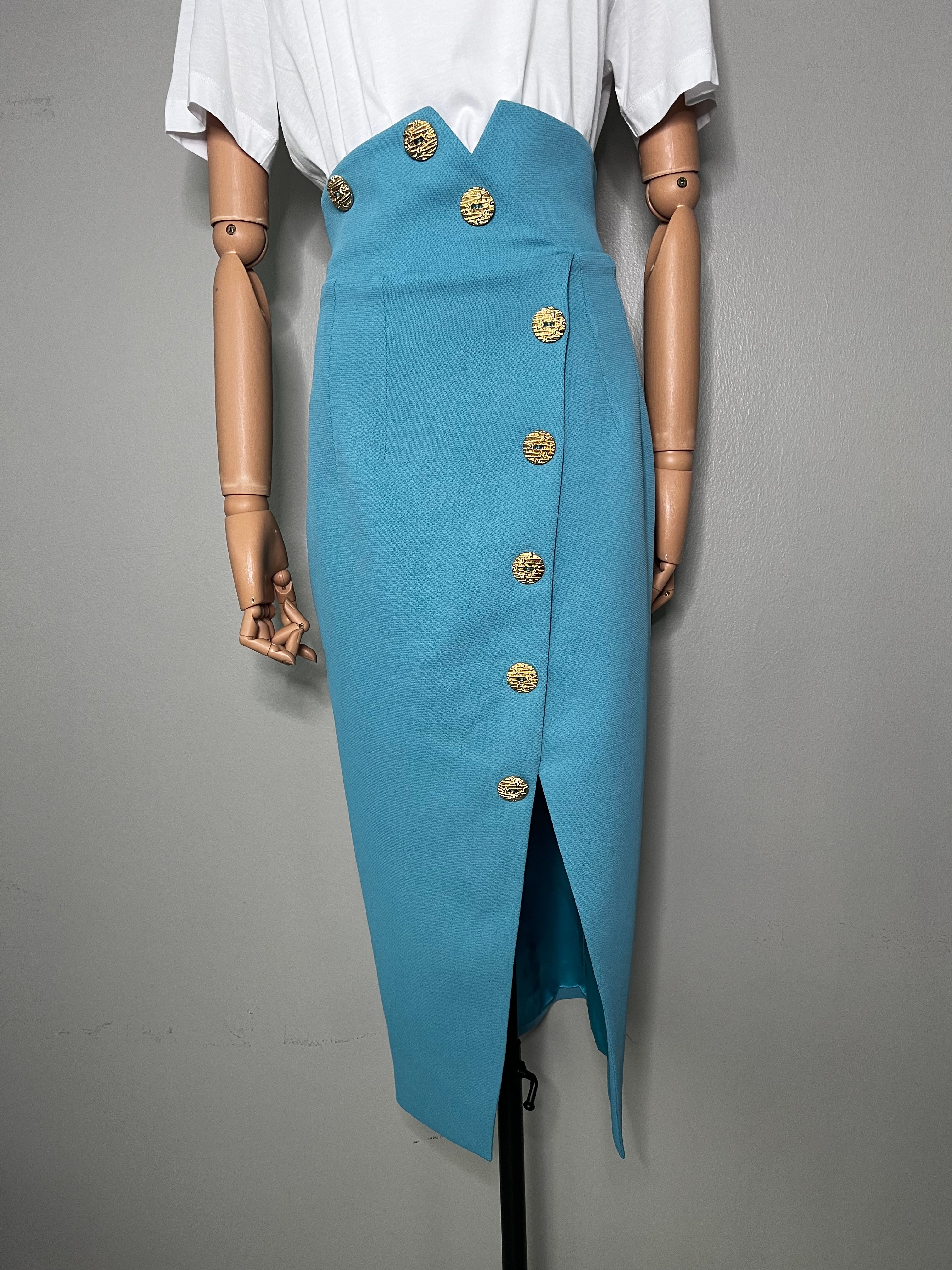 Long sky blue skirt with slit at the middle and big gold buttons all the way down and on the waistline. - GLAMODA.