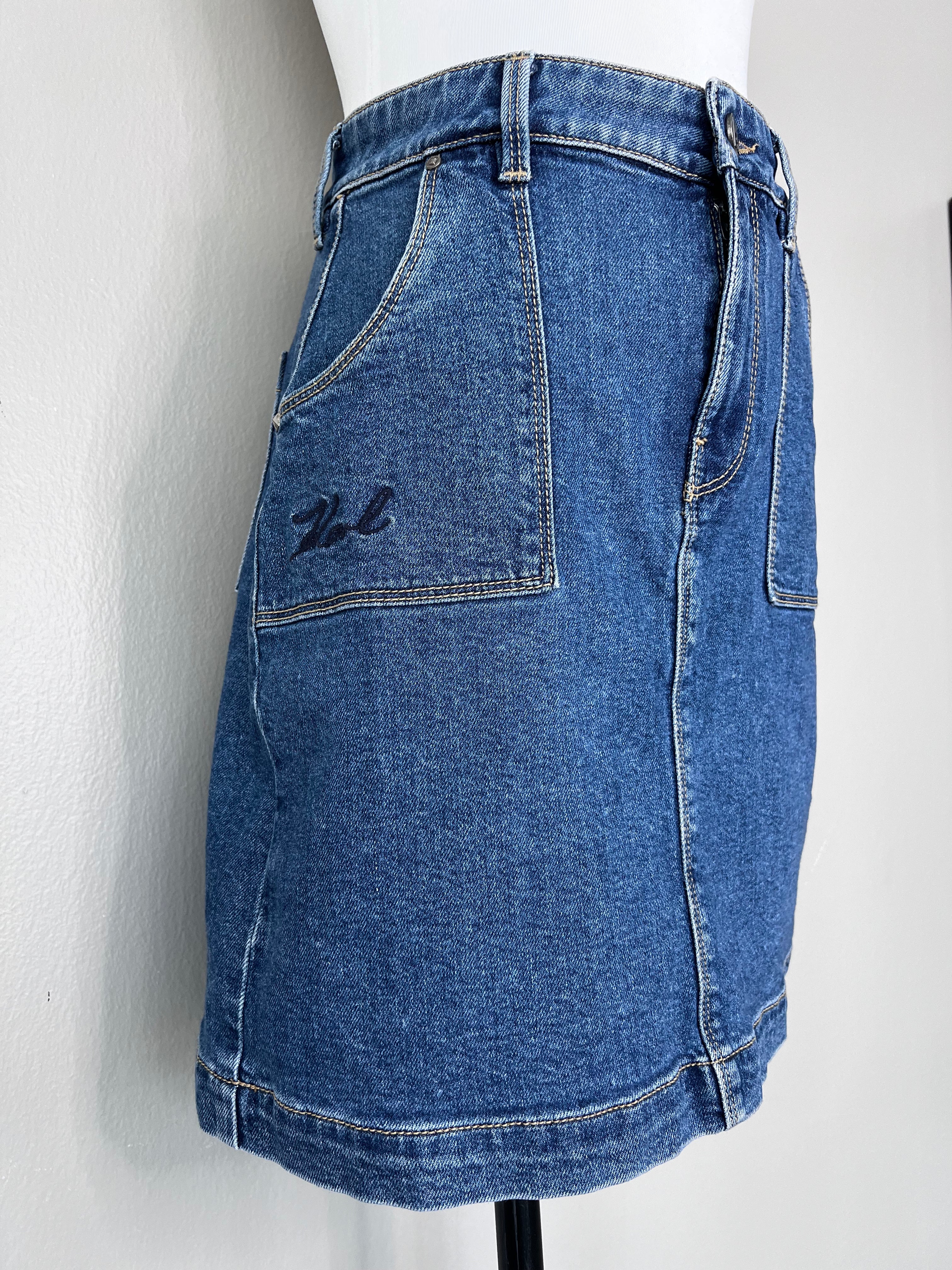 Blue short denim skirt with pockets on either side at the front and back, and brand logo at the back pocket.- KARL LAGERFELD DENIM